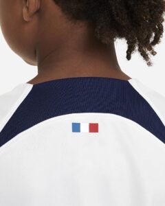 Back view of a white and dark blue sports jersey with a small French flag emblem on the upper back near the collar