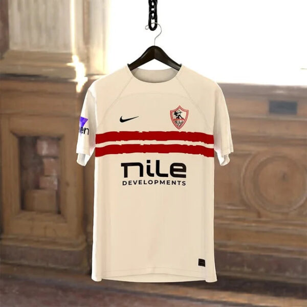 White soccer jersey on a hanger with two red stripes, crest on the chest, Nike swoosh, and Nile Developments sponsor.