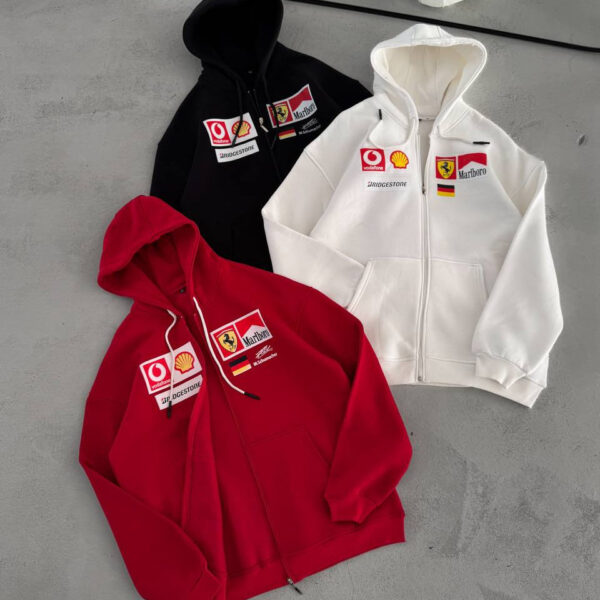 Red, white, and black hoodies with sponsor patches laid on a gray floor.