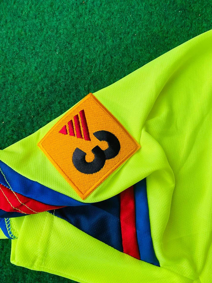 photo_2_2024-02-18_01-47-59_8a212a48-771f-4bd5-908e-10733a5def5e | UAE SPORT STORE Neon yellow safety jacket on green turf with an orange patch showing a bold black number 3 and red stripes nearby.