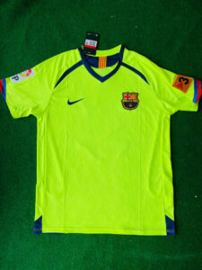 photo_5_2024-02-18_01-47-59_04129057-b8a5-4557-836d-7a65a8a9f8c9 | UAE SPORT STORE Neon yellow FC Barcelona goalkeeper jersey laid on green turf with club crest, Nike logo, and league patches on sleeves.