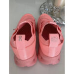 Back view of pink athletic sneakers with pull tabs and chunky soles on a reflective surface.