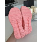 Upward view of pink rubber shoe soles with rectangular tread patterns and deep grooves.