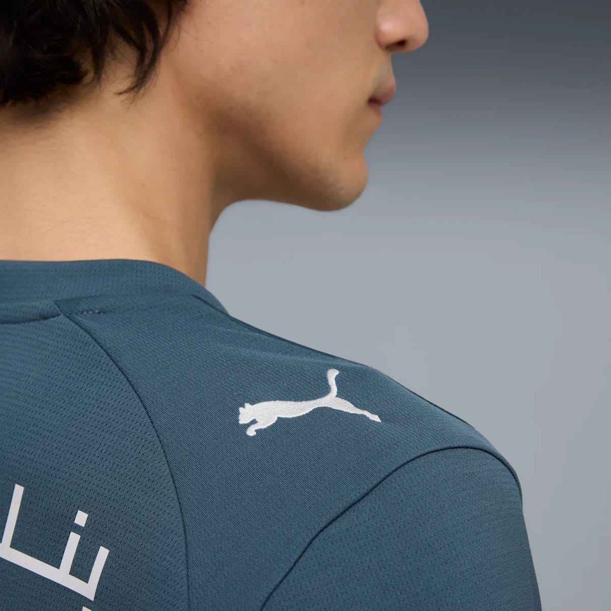 Back view of a person wearing a blue athletic jersey with a white Puma logo on the shoulder.