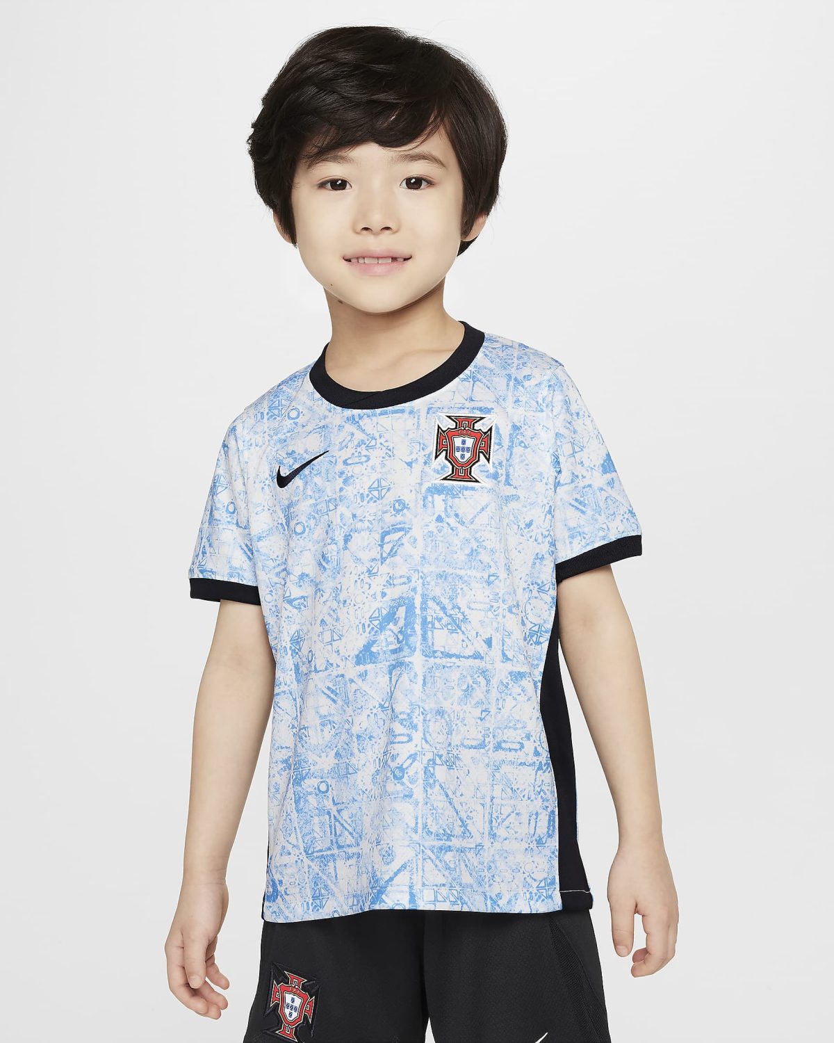 Portrait of a smiling young boy wearing a Portugal national team football jersey against a plain light background.
