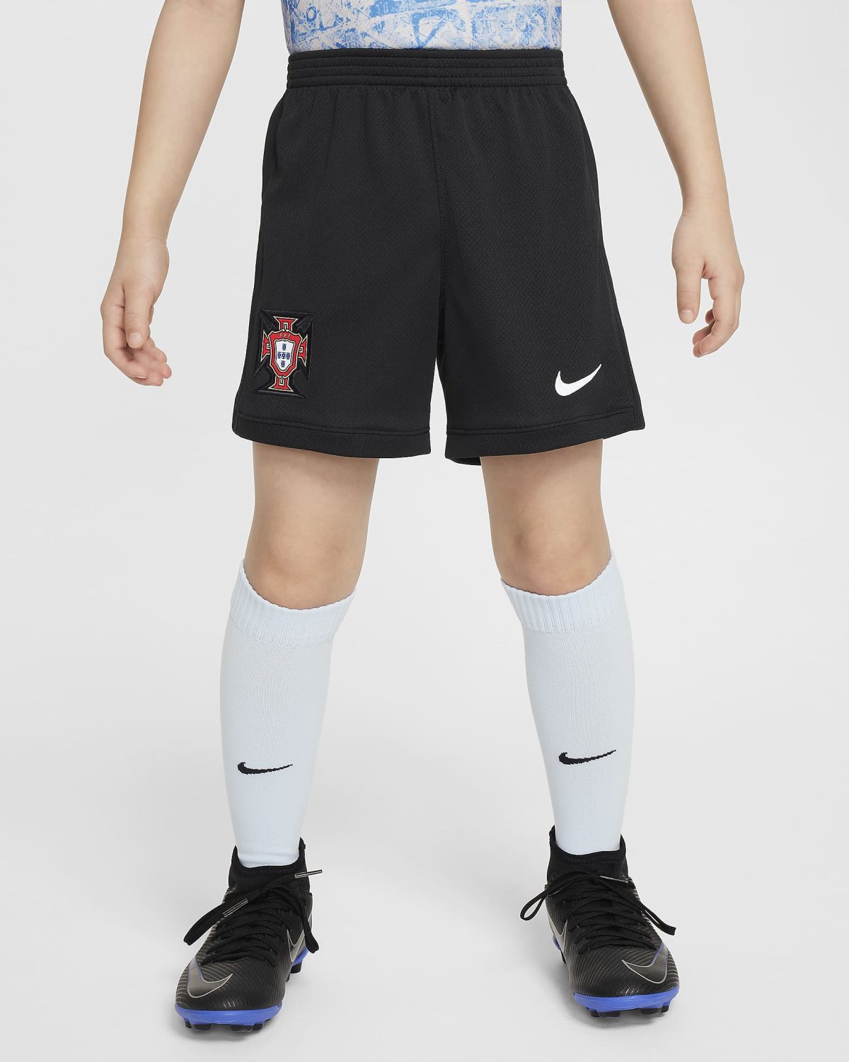 Child's legs in a soccer outfit: black shorts with Portugal crest on the left and a white Nike swoosh, light blue socks, and black cleats.