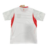 White sports jersey with red side panels shown from the back, tag attached at neck, subtle logo near collar