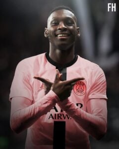 Smiling footballer in a pink Paris Saint-Germain jersey crosses forearms to form an X.