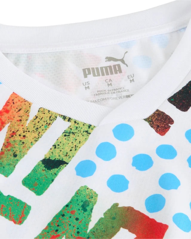 puma__pum-778589-35__detailview01_640x800_crop_center_b6277332-a7e4-461f-9f4a-d82ac0baada9 | UAE SPORT STORE Close-up of a white T-shirt collar revealing the Puma label and colorful, abstract print with blue dots.