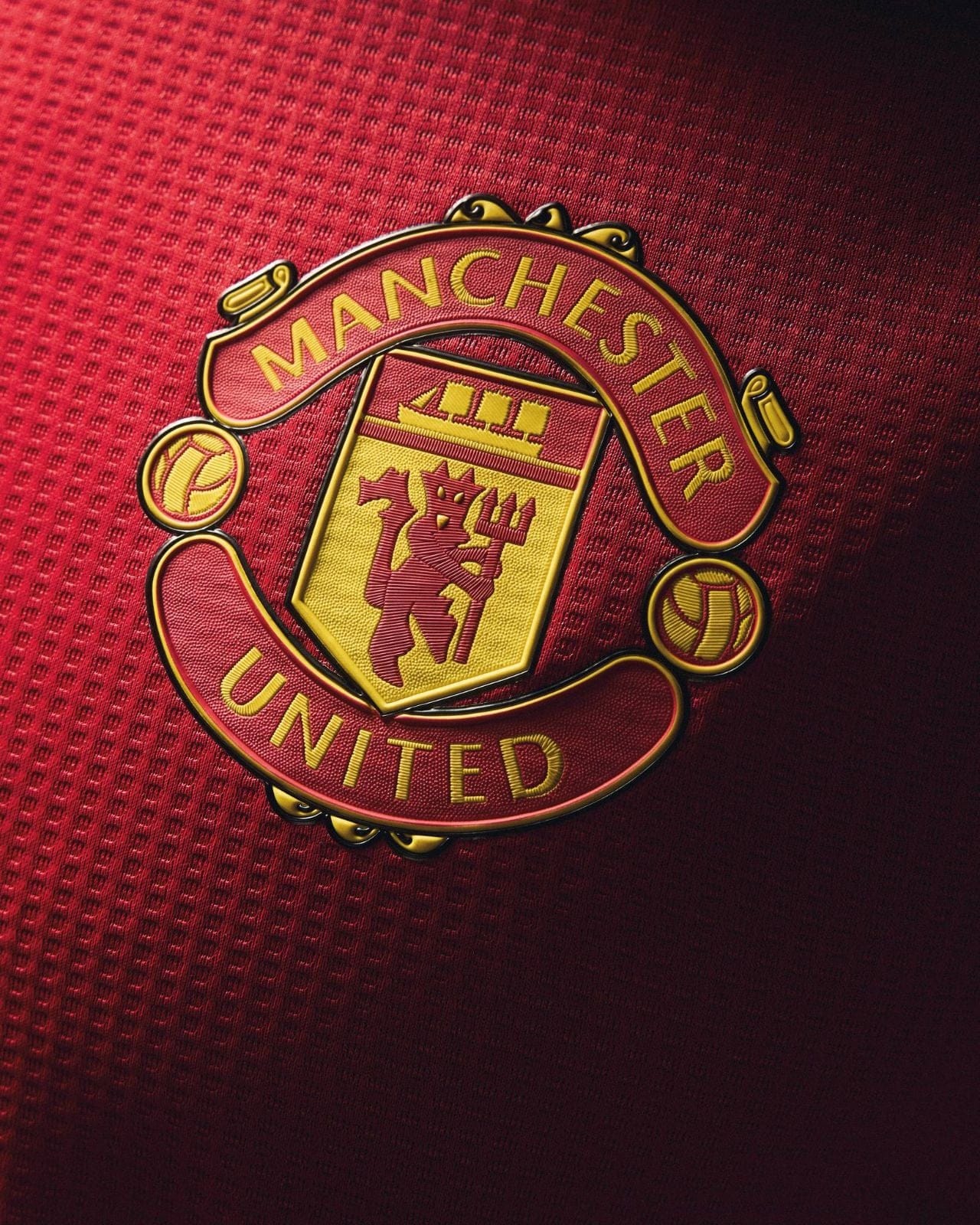 qvOj9Droea9ykMF | UAE SPORT STORE Manchester United crest on a red textured jersey, with gold and yellow detailing in the emblem.
