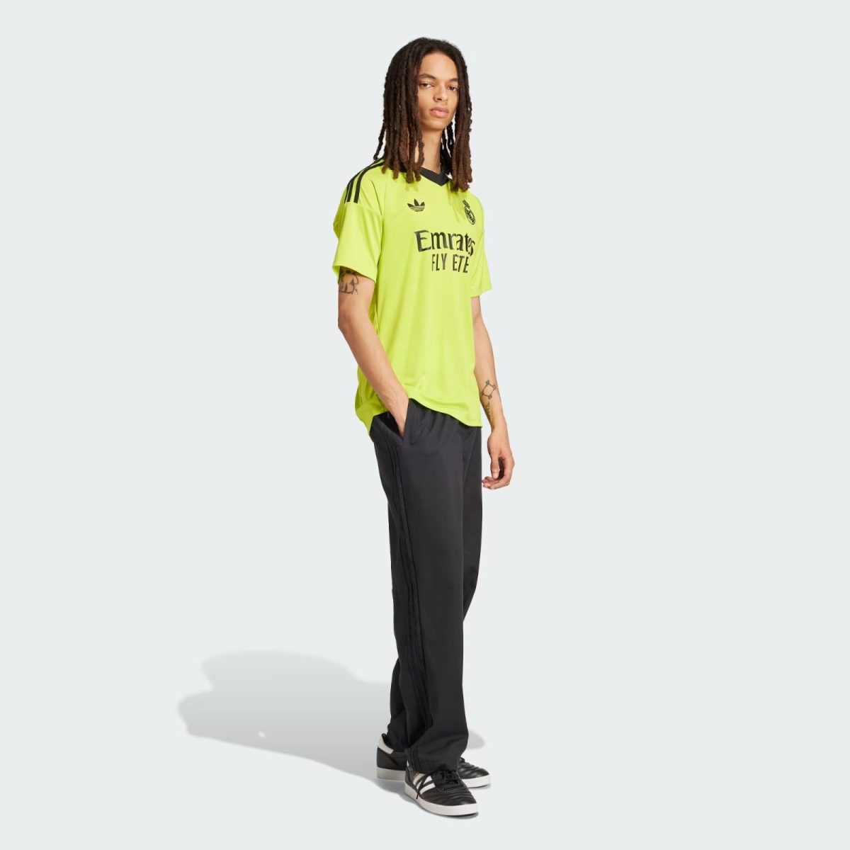 Person standing in a neon yellow Real Madrid soccer jersey and black pants, facing slightly right.