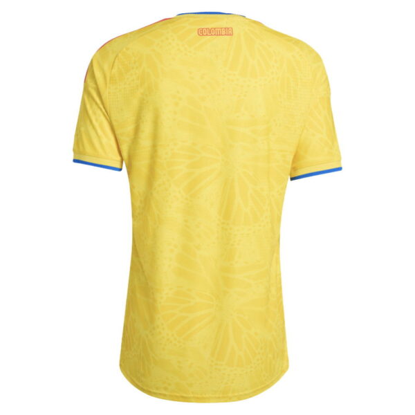 Back view of a yellow Colombia national team soccer jersey with blue trim on sleeves and a subtle tie-dye pattern; COLOMBIA text near the collar.