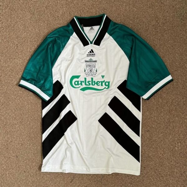 White football jersey with green sleeves and black diagonal panels, featuring Carlsberg sponsor logo and club crest (Adidas).