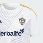 rkrlBqeirBf2wvP | UAE SPORT STORE White LA Galaxy soccer jersey close-up with pinstripes, team crest, and Herbalife sponsor text visible, yellow shoulder trim.