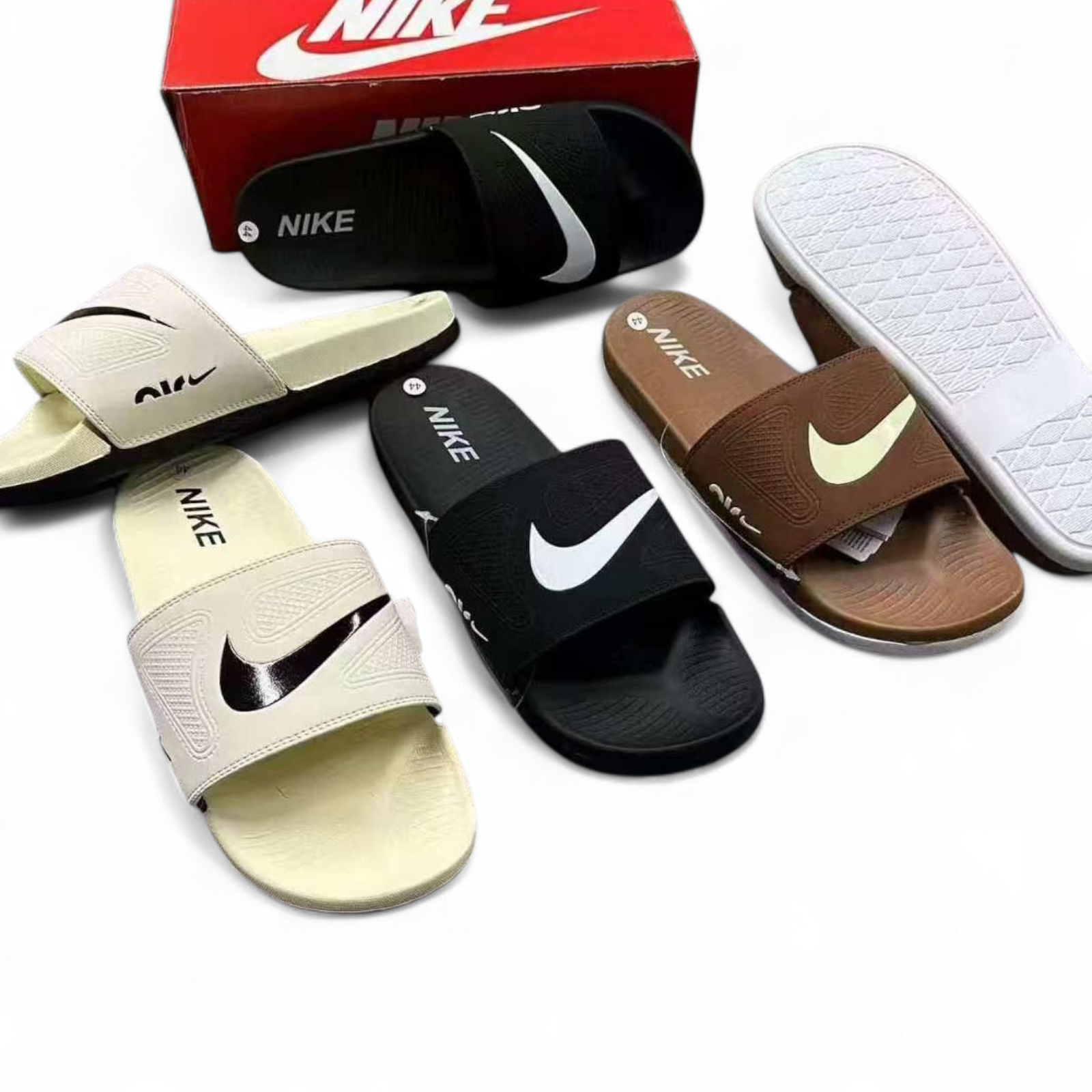 rn-image_picker_lib_temp_02469c13-4858-4ce4-bc58-3d31681452ee Collection of Nike slide sandals in beige, black, brown, and white with a red Nike box in the background.