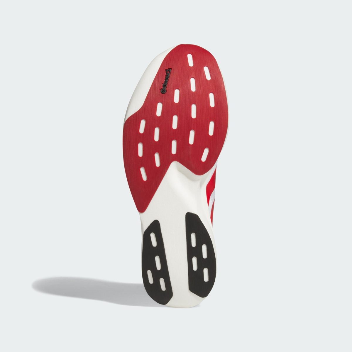 Close-up of a red shoe sole with white vent holes and a small Continental logo on the side against a light background.