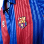 rn-image_picker_lib_temp_03f551c2-1c73-4a5b-baed-d11c35f2e917 | UAE SPORT STORE Close-up of a blue and red striped FC Barcelona jersey featuring the club crest on the chest.