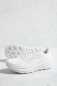 White athletic sneakers with textured soles resting on a pale blue surface.