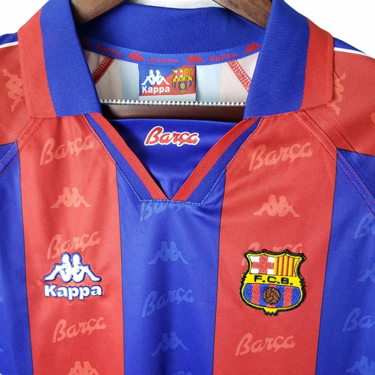 Close-up of a FC Barcelona jersey neckline: blue and red vertical stripes, Kappa logos, and the Barça crest visible on the chest area.