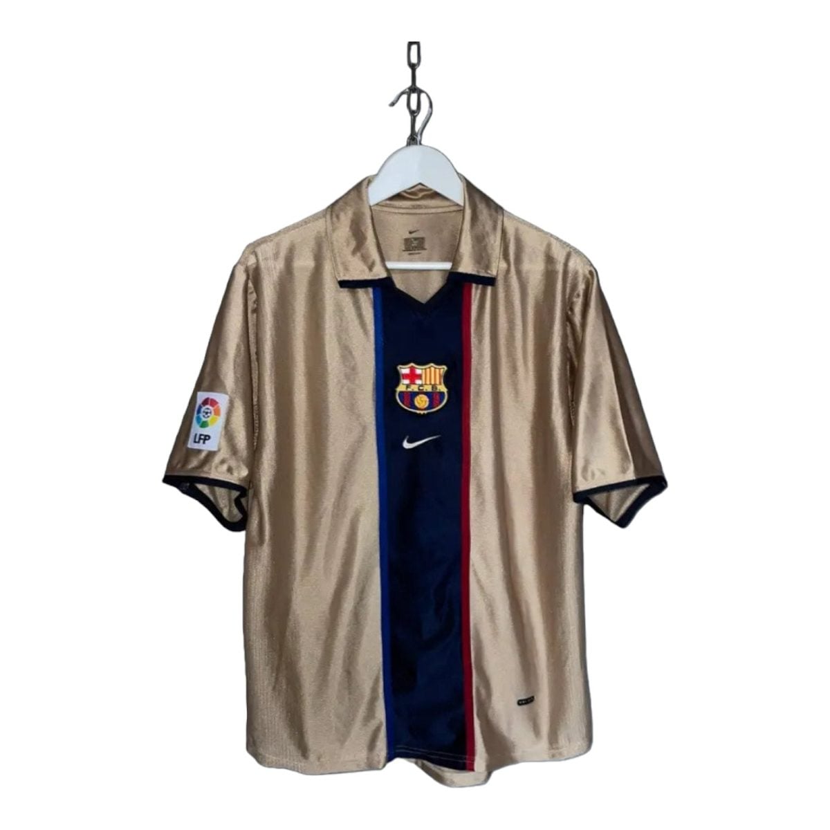 Beige FC Barcelona soccer jersey on a hanger with a dark blue center panel, red stripe, and team crest on the chest