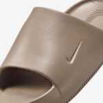 Beige Nike slide sandal with a single strap and textured footbed (close-up).
