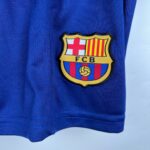 Close-up of a blue sports jersey with the FC Barcelona crest partially visible on the right side, showing yellow shield and red/blue stripes.