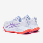 Pair of light lavender ASICS running shoes with orange sole on a white background, angled to show sides and laces.