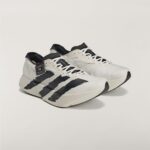 White and black athletic sneakers with three bold black stripes on the sides, placed on a light background, cropped bottom portion visible.