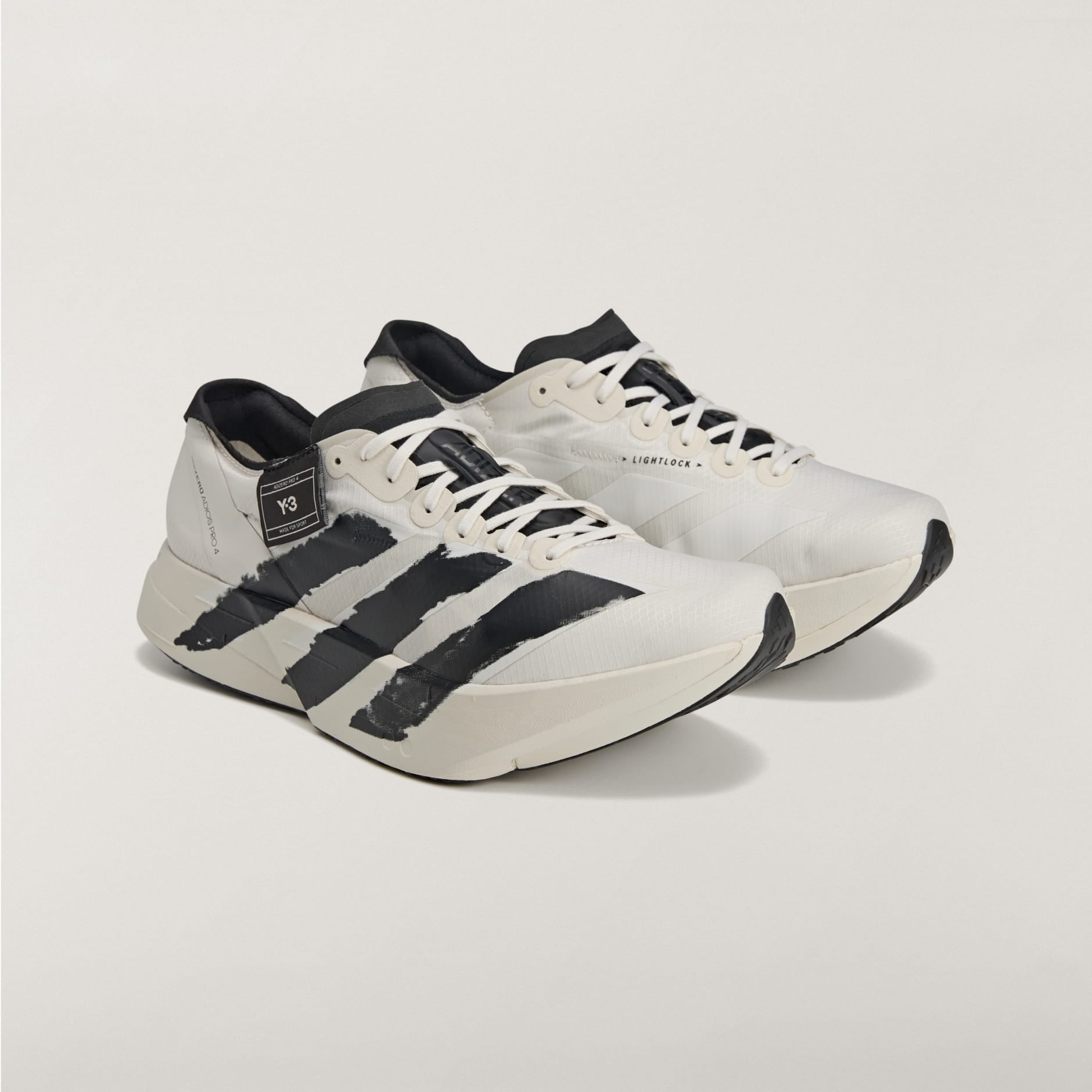 rn-image_picker_lib_temp_0a8a935a-f022-4691-8e54-f497239bded7 White and black athletic sneakers with three bold black stripes on the sides, placed on a light background, cropped bottom portion visible.