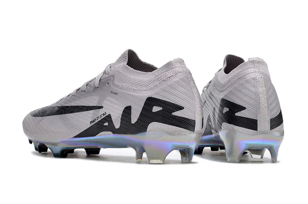 rn-image_picker_lib_temp_0d65659a-66f1-455d-a41f-4d6cab181b5d | UAE SPORT STORE Pair of light gray soccer cleats with black accents and iridescent sole plates on a white background.
