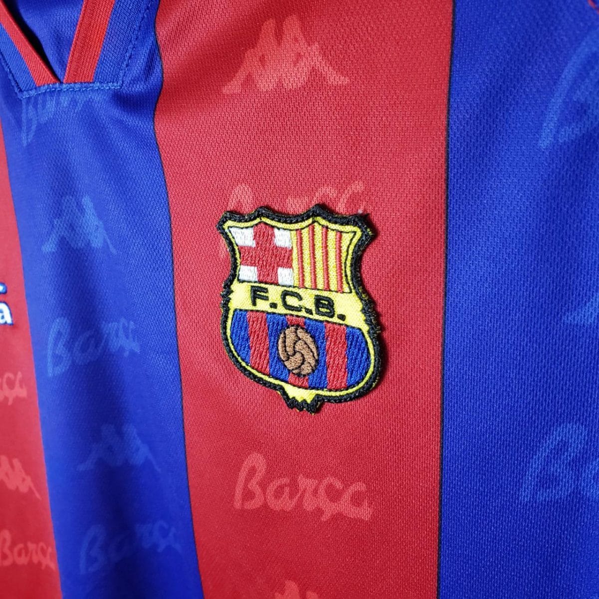 Close-up of FC Barcelona crest on a blue and red striped jersey.