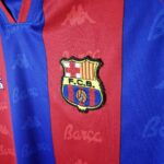 rn-image_picker_lib_temp_0f4cceeb-a0f8-4d4c-867c-192eedda5e68 | UAE SPORT STORE Close-up of FC Barcelona crest on a blue and red striped jersey.