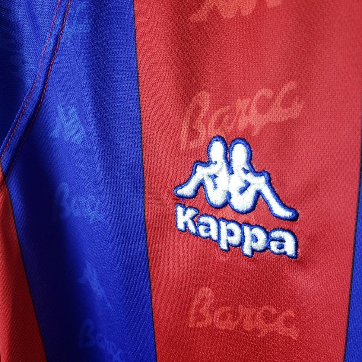 Red and blue striped sports jersey with a white embroidered Kappa logo on the red panel.