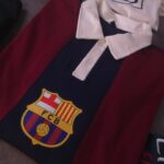 Red and navy FC Barcelona polo shirt with white collar and club crest visible on the chest area.