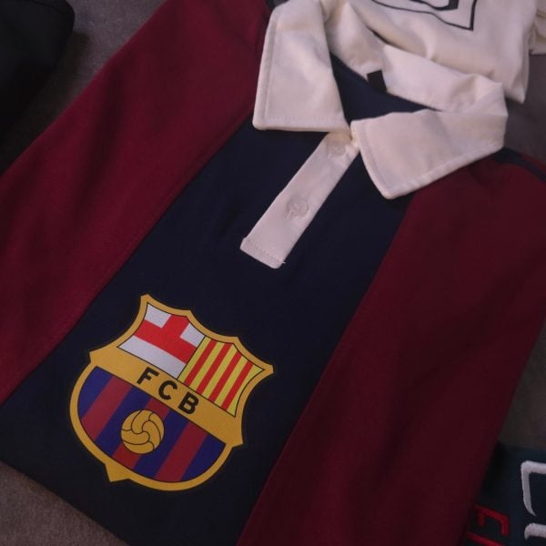 Red and navy FC Barcelona polo shirt with white collar and club crest visible on the chest area.