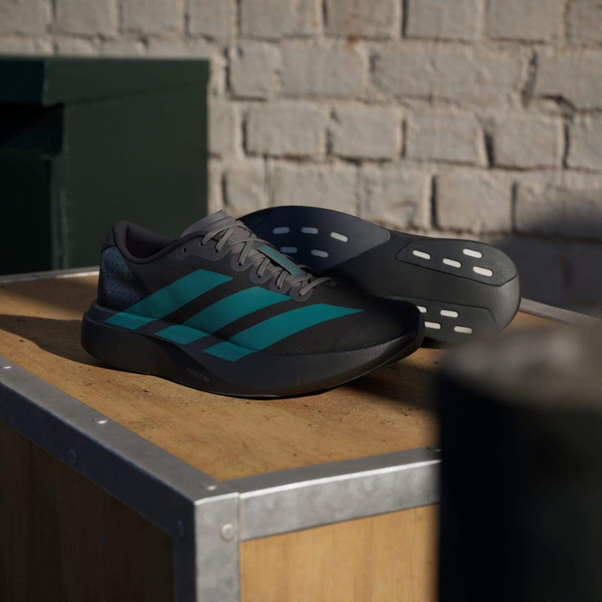 Grey athletic shoes with teal stripes resting on a wooden bench against a brick wall behind them.