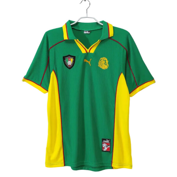 Green football jersey with yellow side panels and red piping, featuring team crest and Puma logo, hanging on a hanger.