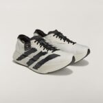 Pair of white sneakers with bold black stripes and thick off-white soles, shown from a low angle, Adidas Y-3 branding visible on the side.