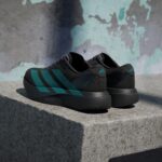 Two black sneakers with teal stripes resting on a concrete step in a low-angle shot.