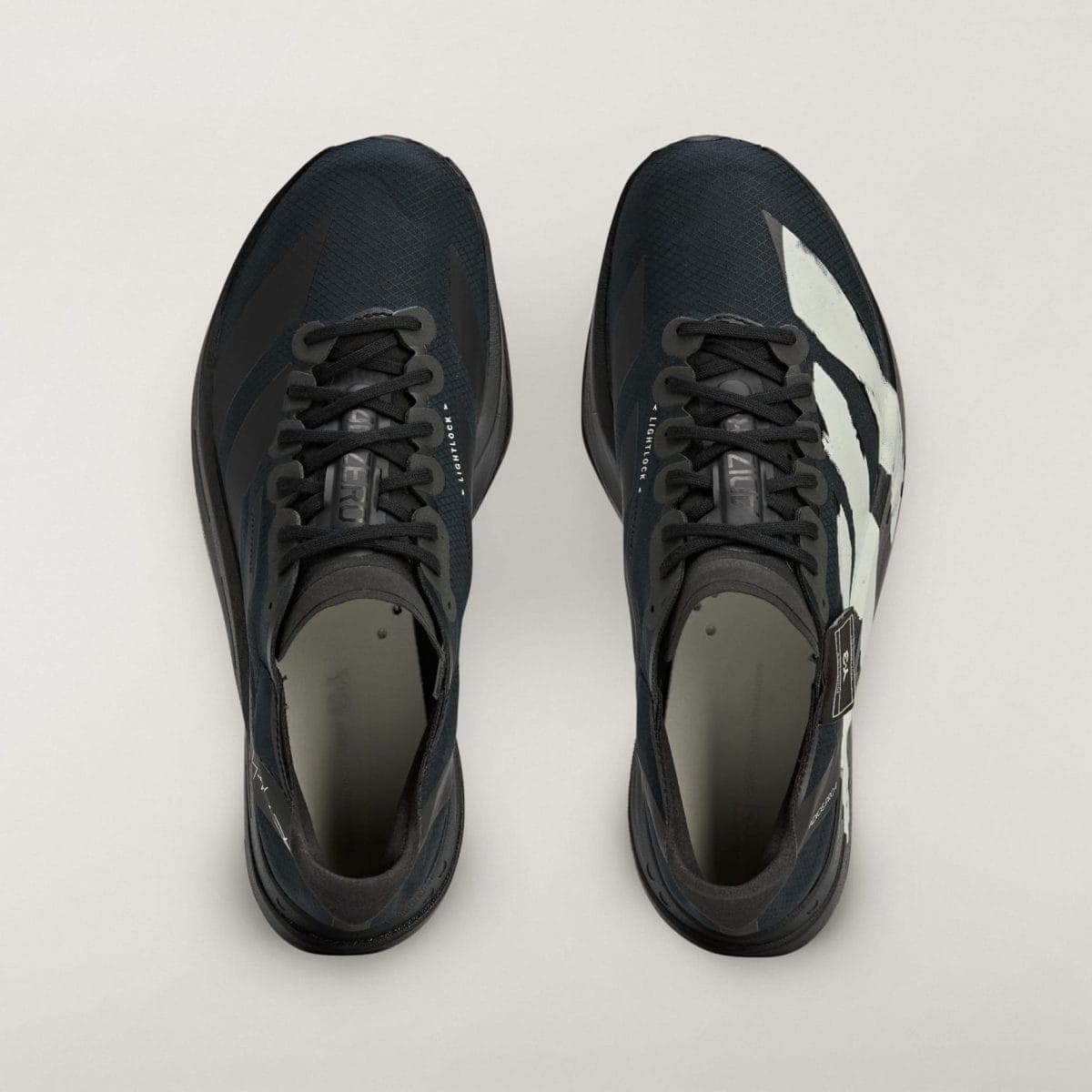 Top-down view of two dark athletic sneakers side by side on a pale background, viewed from above.