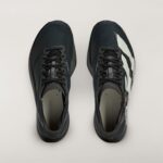 Top-down view of two dark athletic sneakers side by side on a pale background, viewed from above.