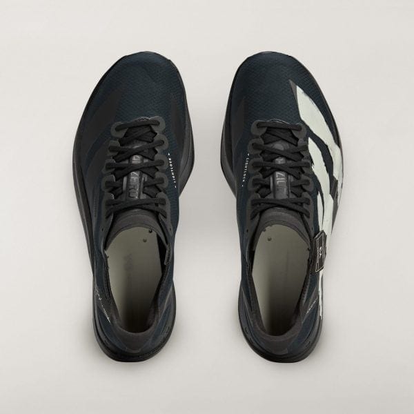 Top-down view of two dark athletic sneakers side by side on a pale background, viewed from above.