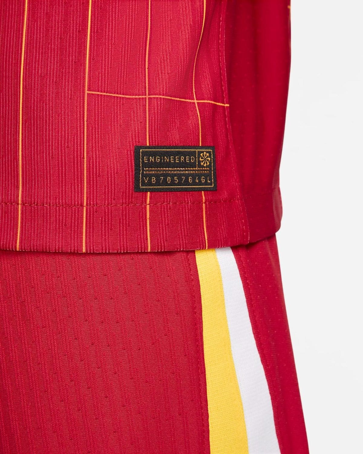 Close-up of red fabric with yellow piping and a black tag reading ENGINEERED near the hem.