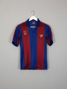 rn-image_picker_lib_temp_22f9a94e-eef1-49f4-98f1-f63704ba6b1b | UAE SPORT STORE Barcelona football jersey with blue and red vertical stripes on a white hanger.