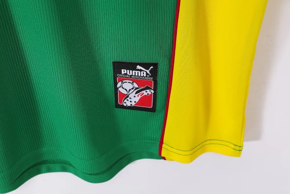 rn-image_picker_lib_temp_2489da80-7939-444d-b5c7-fb75f095715d | UAE SPORT STORE Green sports jersey with a yellow side panel and a black PUMA Official Merchandise patch featuring a football graphic.