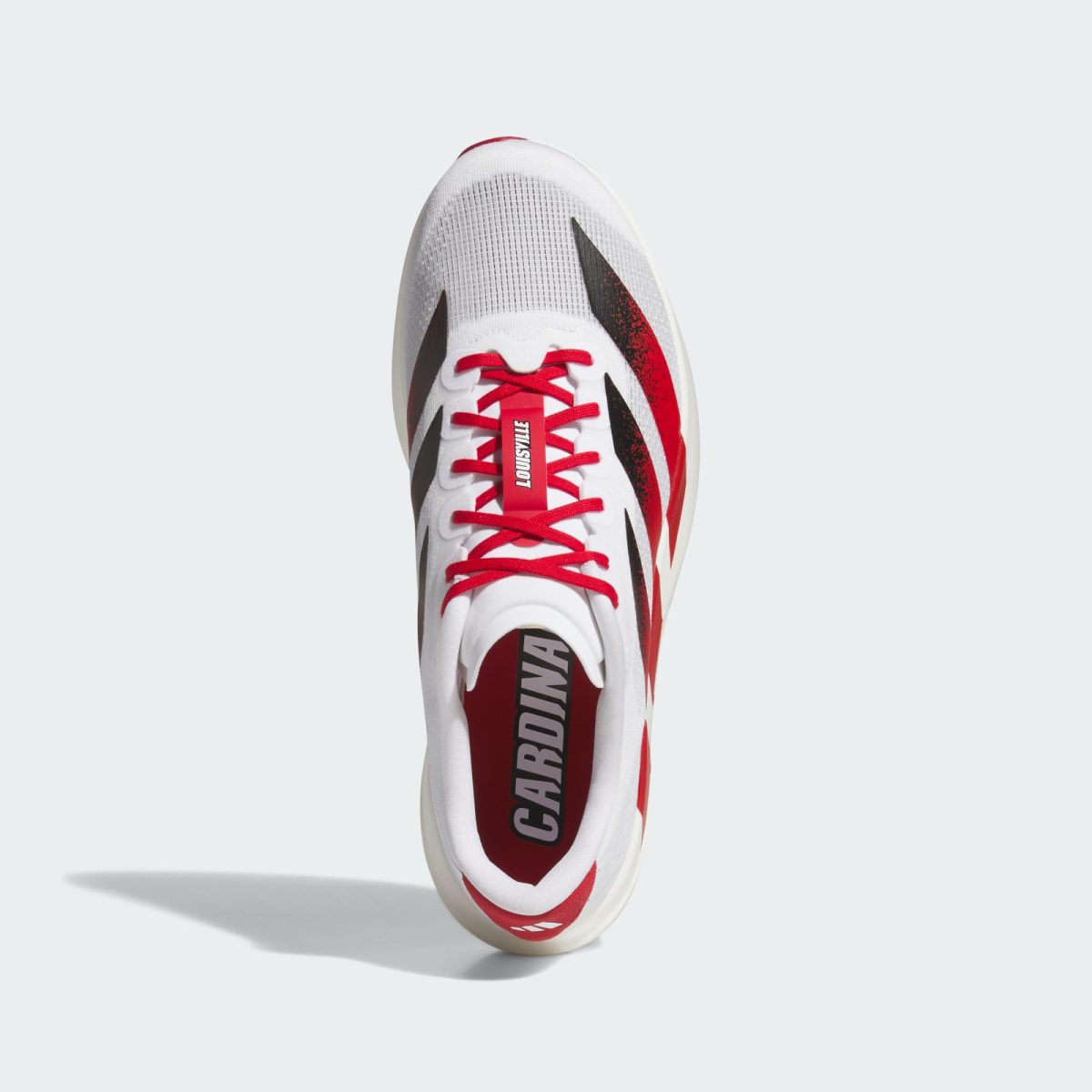 Top view of a white and red athletic sneaker with red laces and Louisville branding on the tongue, hanging midair.