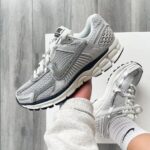 Light gray Nike running shoes with a textured mesh upper and chunky sole held over a white box.