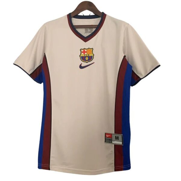 Beige FC Barcelona jersey on a hanger with club crest, Nike swoosh, and red/blue side panels.