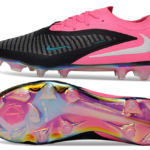 Nike soccer cleat with pink heel, black striped upper, light blue swoosh, and iridescent outsole shown from side and bottom (product image).