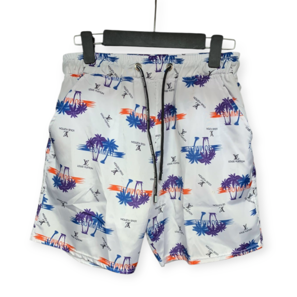 White Louis Vuitton swim shorts with blue, purple, and orange palm tree print, hanging on a black hanger